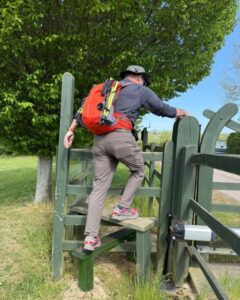 A hiker climbing over a stile in the countryside