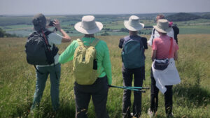 Photo of a group of hikers taken from behind standing on top of a hill looking out at the view.