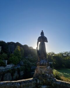 A stone statue on a bridge silhouetted against the morning sun.