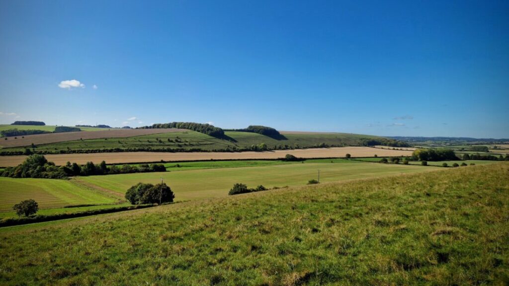 Rolling green fields and hill stretch off into the distance under a bright blue September sky