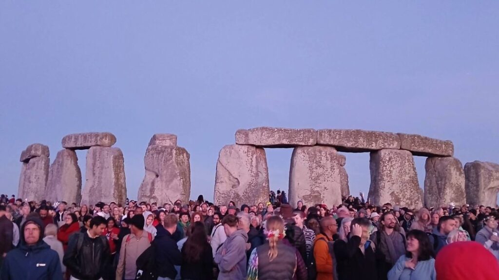 Photo of Stonehenge at dawn with crowds gathered celebrating the summer solstice