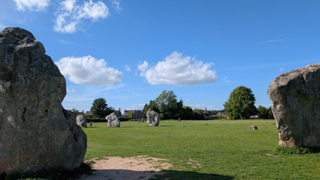 view of a Neolithic stone circle with roofs of village cottages in the distance