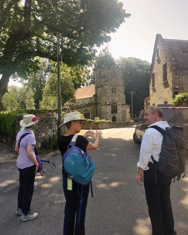 Tour guide David Howell is standing in a pretty village explaining something to two guests on the guided trip.