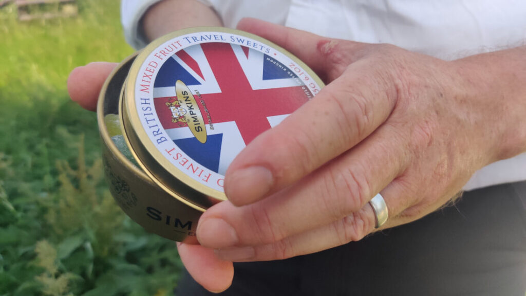 Close up of someone's hands holding a tin of sweets with the lid slightly open.
