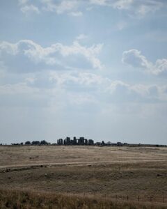 View of Stonehenge from a distance on a bright summer's day over agricultural fields.