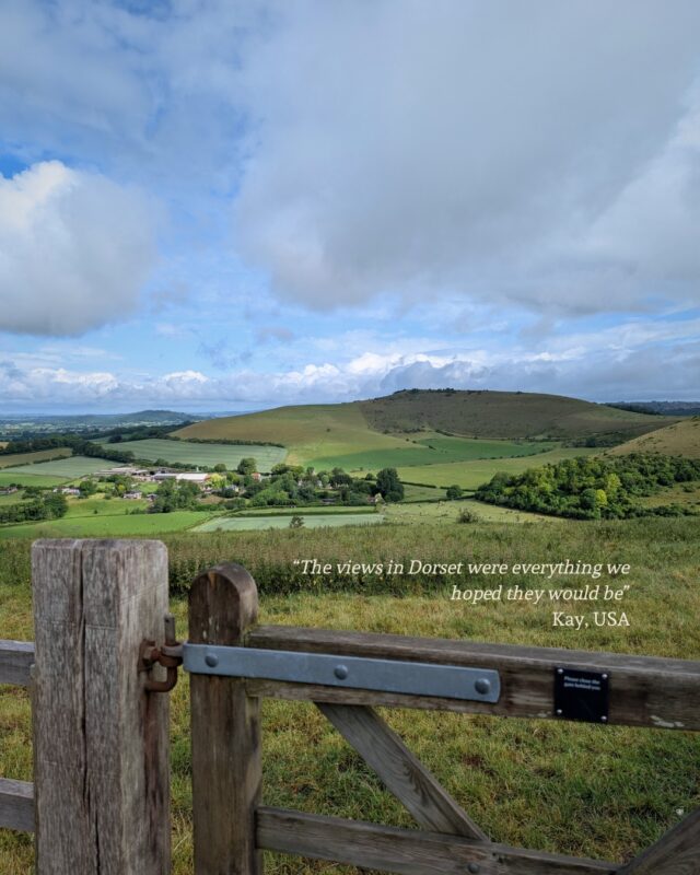 View out over the lush green countryside of Dorset. A wooden gate is in the foreground and rolling hills in the background. Next to the gate is a testimonial: “The views in Dorset were everything we hoped they would be” Kay, USA