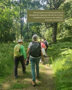 A group of hikers walks on a footpath through woodland.