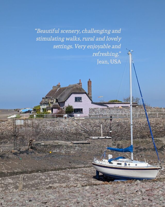 View of a boat in a harbour with the tide out and thatched cottages in the distance. A guest testimonial is shown in the top right corner: “Beautiful scenery, challenging and stimulating walks, rural and lovely settings. Very enjoyable and refreshing.” Jean, USA