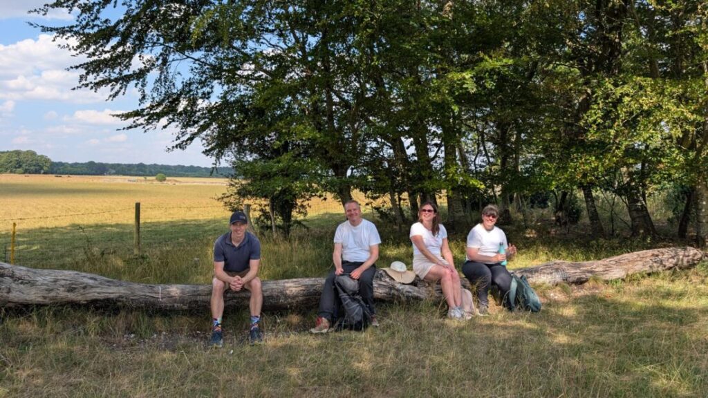 A photo of four members of the Foot Trails team sat on a log surrounded by trees and fields.