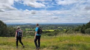Two hikers walking on top of a hill with their heads turned to look at the view.