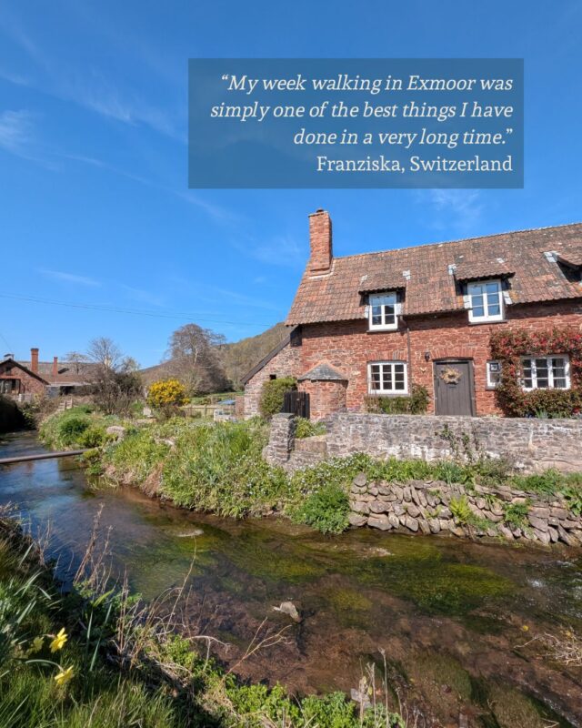View of a red-brick cottage next to a river under a bright blue sky. There is a guest testimonial in the top right corner: “My week walking in Exmoor was simply one of the best things I have done in a very long time.” Franziska, Switzerland