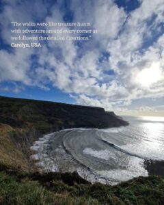 View of a secluded bay from the surrounding cliffs. A guest quote is placed in the top left corner: “The walks were like treasure hunts with adventure around every corner as we followed the detailed directions.” Carolyn, USA