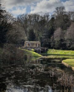 View of the Palladian bridge in Prior Park from a distance showing the river winding towards the bridge
