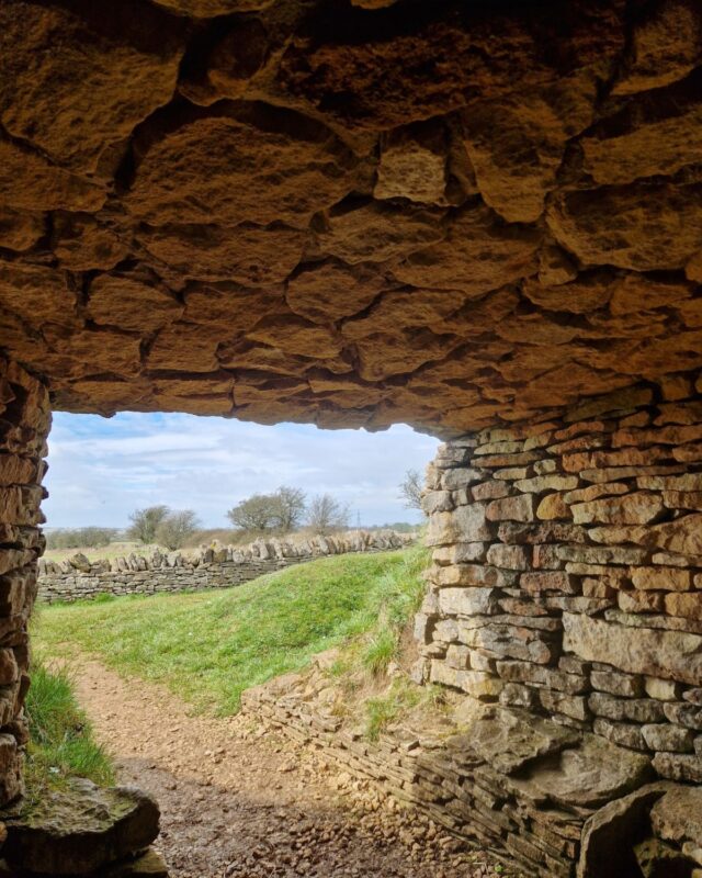 View from within the dark stone entrance to a Neolithich long barrow out into the countryside beyond.