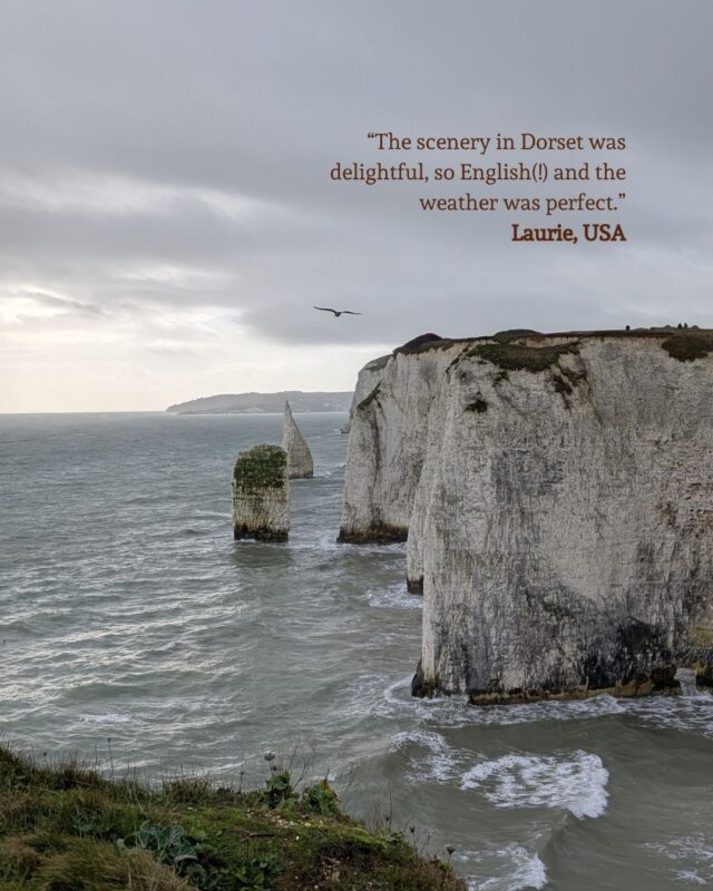 View of dramatic chalk cliffs and a grey sea under a grey cloudy sky with a guest testimonial positioned in the top right corner: “The coastal areas are completely different than those in the US, and so very gorgeous!!!” Maryellen, USA