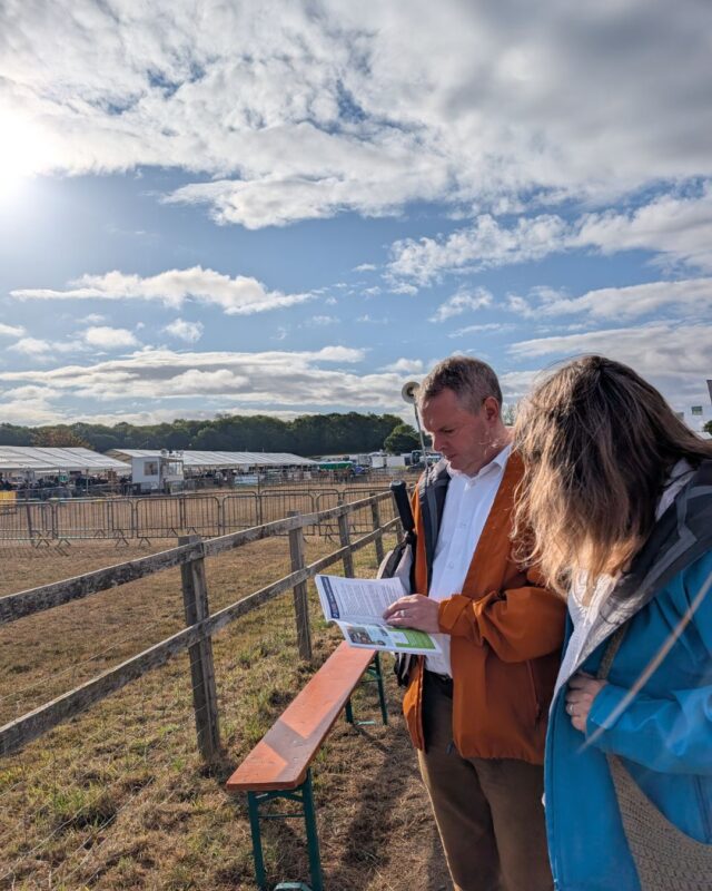 Foot Trails Co-Founders David and Alison standing next to an exhibition ring and reading the program of events at a country show.