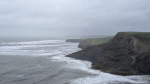 View of the cliffs of Dorset coast in winter stretching out into the distance under a hazy gray sky.