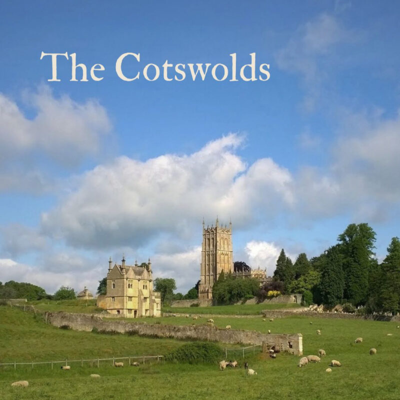 A view of rolling green fields with sheep grazing in the foreground and a grand country house and large church tower in the background. The title 'The Cotswolds' is shown in the top left corner.