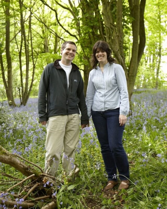 A young Alison and David Howell (Foot Trails Foundesr) are standing in woodland smiling at the camera and holding hands