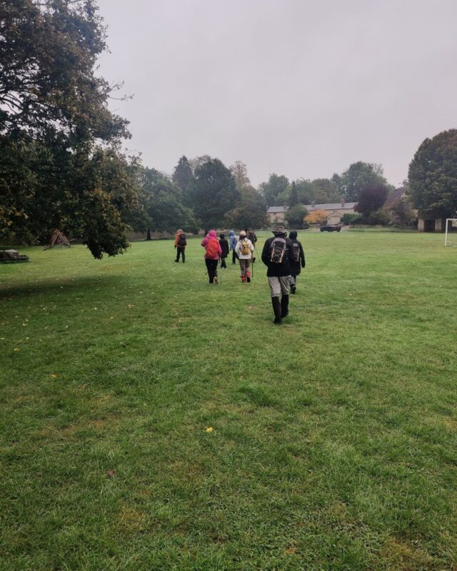 A group of hikers walking across a field under a grey sky