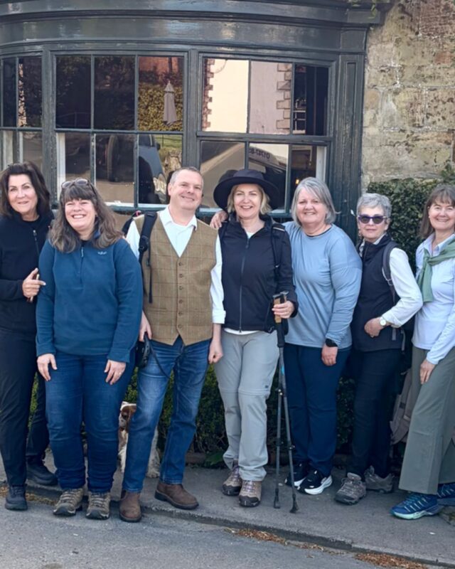 Foot Trails Co-Founders Alison and David Howell standing in a group of six female hikers smiling and laughing at the camera.