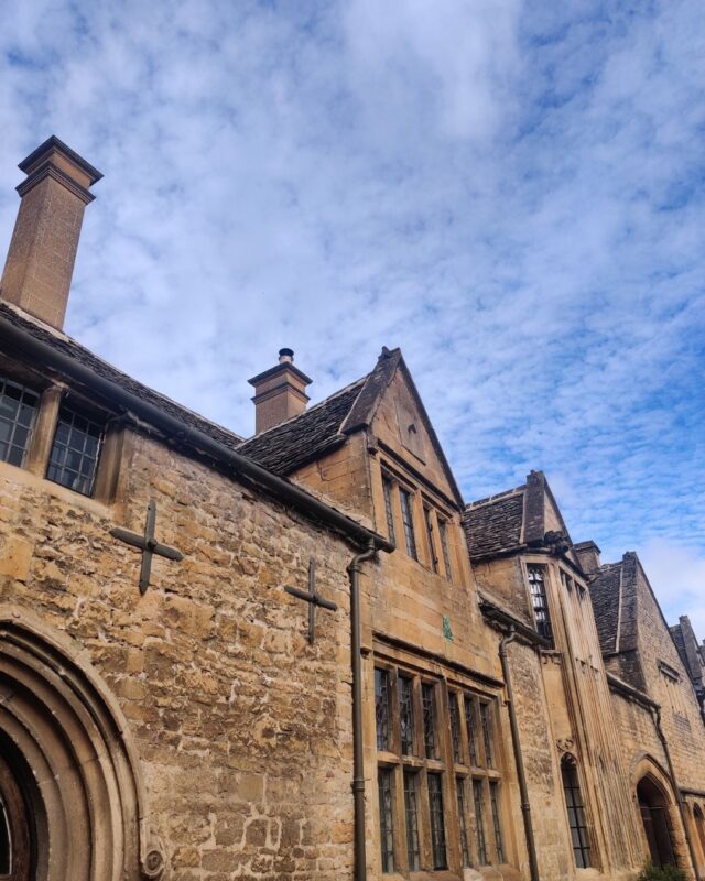 An image of grand Cotswolds stone cottages against a blue sky.