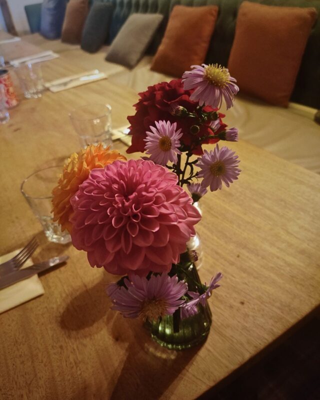 A vase of fresh flowers stands on a table laid for dinner in a country inn
