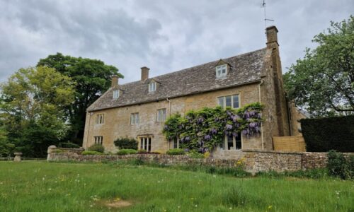Cotswolds cottage in the meadow A classic Cotswolds cottage in front of a village green