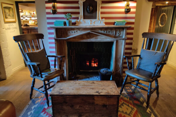 Two wooden chairs in front of a lit fireplace in a country inn